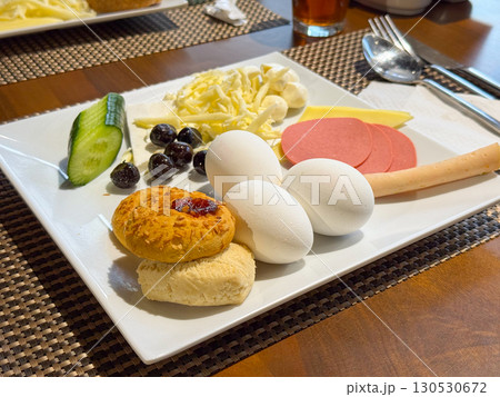 Breakfast plate with boiled eggs, cheese, sausage, vegetables, and pastry. Nutrition, food culture, and lifestyle in hotel dining service. 130530672