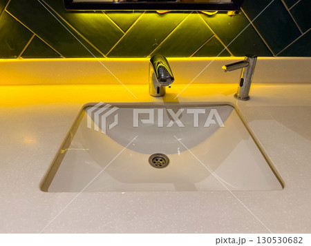 Modern bathroom sink with chrome faucet and yellow light reflection. Hygiene, interior design, and lifestyle details in daily environment. 130530682