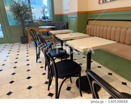 Empty cafe interior with tables, chairs, tiled floor, and green walls. Hospitality, modern design, and daily lifestyle in comfortable social environment. Empty cafe interior with tables, chairs, tiled floor, and green walls. Hospitality, modern design, and daily lifestyle in comfortable social environment. 130530688