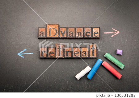 Conceptual image of strategic decision-making with chalk arrows pointing to Advance and Retreat 130531288