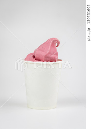 Vibrant pink berry soft serve in white cup, close-up shot on light background 130531603