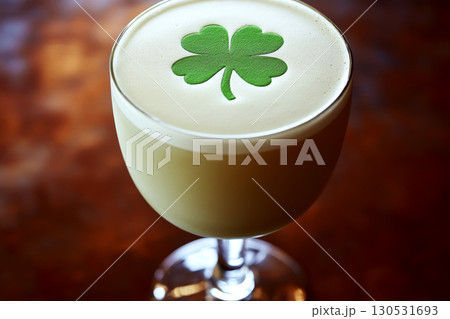 A cocktail glass with a foam top features a green clover design. Concept of celebration and festive drinks. For St. Patrick's Day promotions. A cocktail glass with a foam top features a green clover design. Concept of celebration and festive drinks. For St. Patrick's Day promotions. 130531693