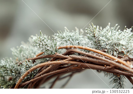 Snow-dusted pine branches intertwined with wooden twigs in a close-up view. Concept of winter, nature, and holiday decor. For seasonal greeting cards 130532225