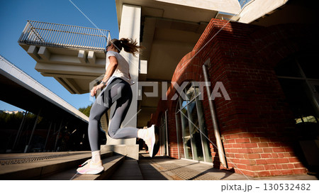 Woman exercising outdoors, running up stairs in modern urban environment Woman exercising outdoors, running up stairs in modern urban environment 130532482