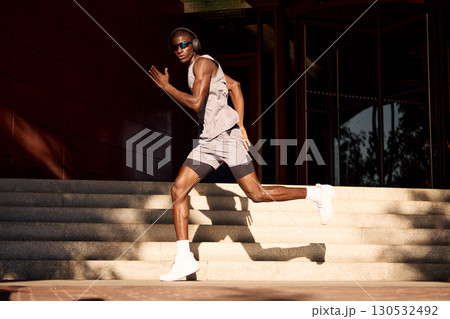 Athletic man sprinting outdoors on urban staircase during sunny day 130532492