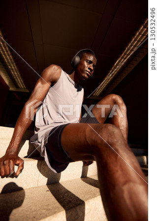 Athletic man relaxing on stairs after an outdoor workout in urban environment 130532496