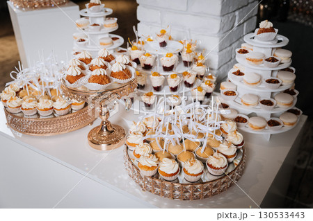 Luxury candy bar with cupcakes, macarons, and desserts on elegant golden trays 130533443