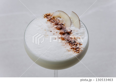 Creamy coconut cocktail with foam and cocoa garnish, served in elegant coupe glass 130533463