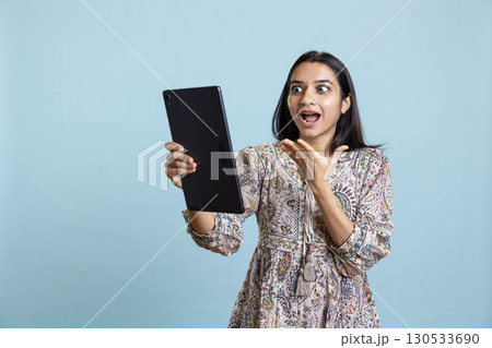 Casual cheerful woman chatting with her friend over video conference online, enjoying relaxation time in studio. Upbeat girl communicating with mate using phone, video call connection. 130533690