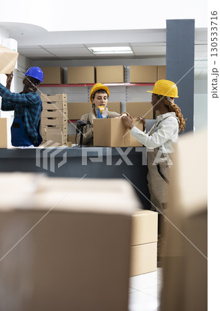 Diverse workers team working together in a logistics center scanning parcels and boxes from the depot space. Warehouse staff manages shipment and quality control using modern registration. Diverse workers team working together in a logistics center scanning parcels and boxes from the depot space. Warehouse staff manages shipment and quality control using modern registration. 130533716
