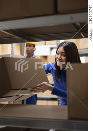Asian woman business owner preparing goods packed in the supply room, managing distribution for a small scale online store. People handling merchandise and stock inventory, local brand. Asian woman business owner preparing goods packed in the supply room, managing distribution for a small scale online store. People handling merchandise and stock inventory, local brand. 130533744