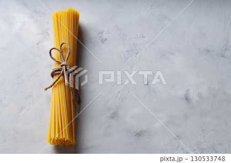 Uncooked Spaghetti Pasta with Natural Rope on Gray Background Top View Copy Space Uncooked Spaghetti Pasta with Natural Rope on Gray Background Top View Copy Space 130533748