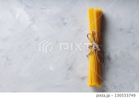 Uncooked Spaghetti Pasta with Natural Rope on Gray Background Top View Copy Space Uncooked Spaghetti Pasta with Natural Rope on Gray Background Top View Copy Space 130533749