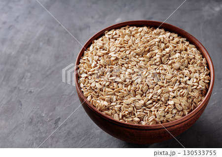 Rolled Oats in Ceramic Bowl on Gray Surface Copy Space 130533755