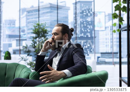 Corporate administrator in negotiation over the phone line, finalizing an agreement with partners after analyzing data and risks. Contacting people regarding international business. 130533875