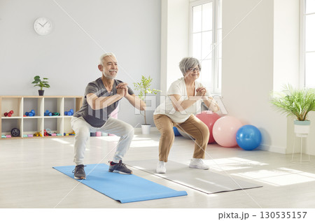 Active happy old senior doing squat morning exercise, sporty people practicing yoga lesson Active happy old senior doing squat morning exercise, sporty people practicing yoga lesson 130535157