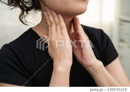 Asian woman touching her neck and throat for thyroid gland problem. 130535229
