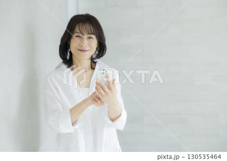 スマホを持つ笑顔の女性　 130535464