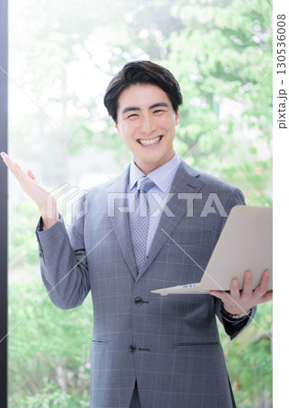 逆光の柔らかい新緑の中でパソコンを持つスーツの男性のカメラ目線 リクルートなど転職のイメージ 逆光の柔らかい新緑の中でパソコンを持つスーツの男性のカメラ目線 リクルートなど転職のイメージ 130536008