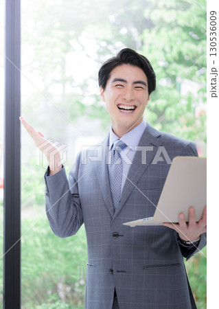 逆光の柔らかい新緑の中でパソコンを持つスーツの男性のカメラ目線 リクルートなど転職のイメージ 逆光の柔らかい新緑の中でパソコンを持つスーツの男性のカメラ目線 リクルートなど転職のイメージ 130536009