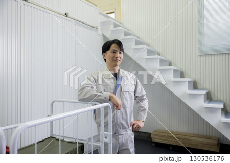 倉庫で台車を押す作業着の男性 130536176