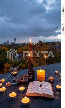 Illuminated Candles and Open Book on Wooden Tabletop with Cityscape View at Dusk 130536630