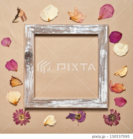 White Wooden Square Frame Surrounded by Dried Flowers and Leaves on Brown Background 130537095