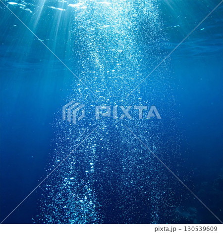 Underwater Bubbles Rising To the Surface in Deep Blue Ocean With Sun Rays 130539609