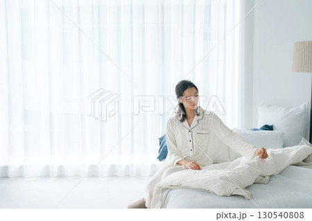 起きて布団を直すパジャマ姿の女性 起きて布団を直すパジャマ姿の女性 130540808