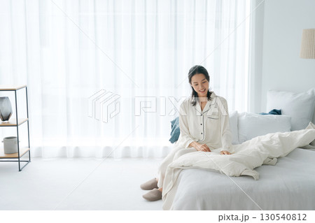 起きて布団を直すパジャマ姿の女性 130540812