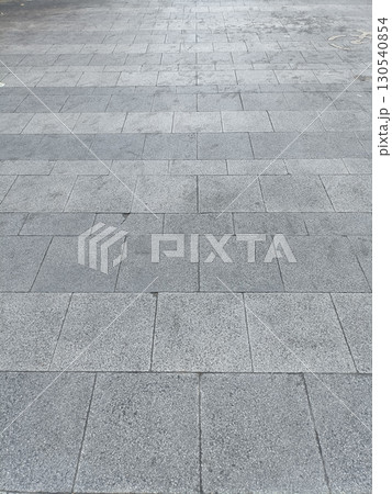 Paved stone walkway with rectangular gray stones arranged pattern, showing slight variations texture and color, creating clean and orderly surface 130540854
