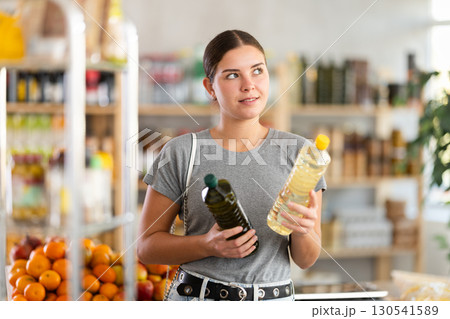 European youth girl choose and buy vegetable oil in store European youth girl choose and buy vegetable oil in store 130541589