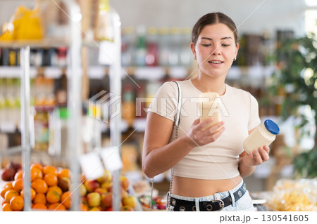 Girl hold bottle, choose and buy mayonnaise in store Girl hold bottle, choose and buy mayonnaise in store 130541605