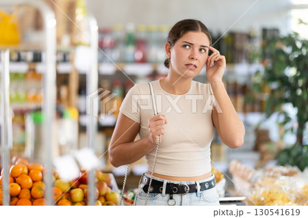 Girl customer suffer from forgetfulness, stand in store and tries to remember planned shopping list. 130541619