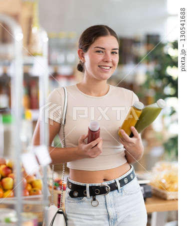 European smiling girl hold bottle, choose and buy smoothie in store 130541688
