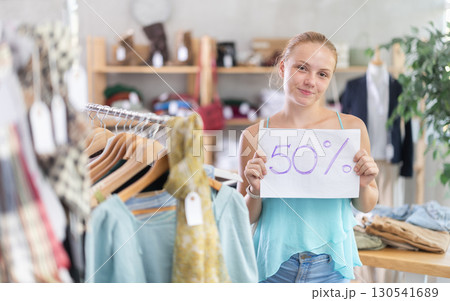 Teen girl holding discount sign in clothing store Teen girl holding discount sign in clothing store 130541689