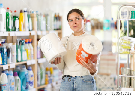 Young woman housewife in household store examines package, chooses paper towel 130541718
