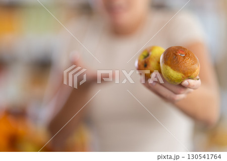 In store, frustrated girl holds rotten fruits in hands, close-up In store, frustrated girl holds rotten fruits in hands, close-up 130541764