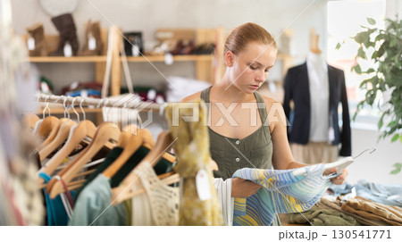 Joyful woman choosing tops in store 130541771