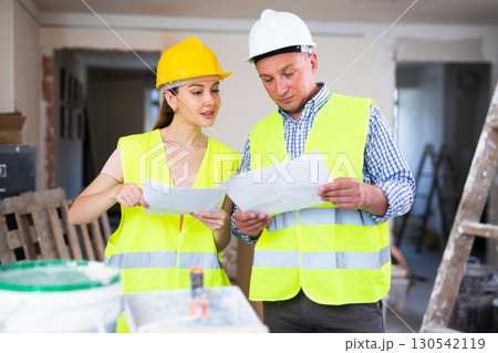 Man and woman builders talking in house Man and woman builders talking in house 130542119