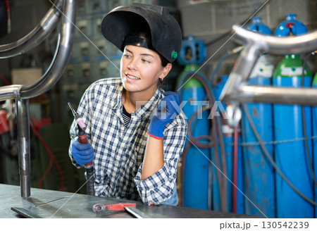 Young woman working with welding machine 130542239