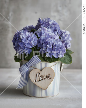 Purple hydrangea flowers in decorative pot with wooden heart and ribbon, creating charming and romantic floral arrangement for special occasions 130542246