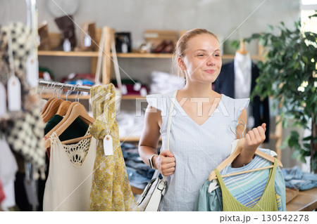 Teenage girl choosing summer clothes in store Teenage girl choosing summer clothes in store 130542278