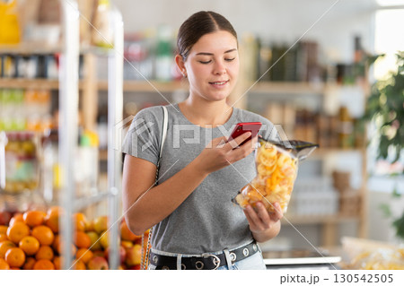In shop youth girl scan QR code and take reading potato mix crisps using phone camera In shop youth girl scan QR code and take reading potato mix crisps using phone camera 130542505