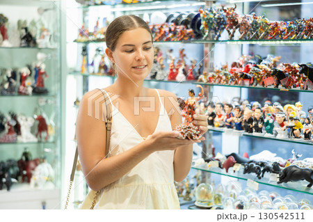Female buyer holds in hands tests figurine she-dancer flamenco in memorable gifts shop 130542511