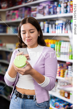 Female customer takes a photo using a mobile phone in cosmetics store Female customer takes a photo using a mobile phone in cosmetics store 130542522