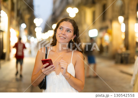 Young woman with phone in her hands walking down the street 130542558