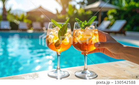An iced citrus cocktail with mint and lime sits on the edge of a cool pool, a refreshing summer beverage 130542588