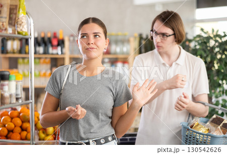 In shop guy stands behind wife, hurling abuse and indignation at her. In shop guy stands behind wife, hurling abuse and indignation at her. 130542626