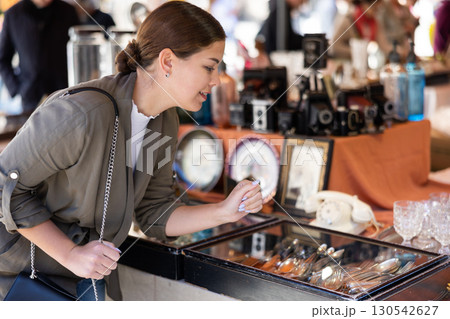 Happy female tourist looking to buy silverware at flea market 130542627